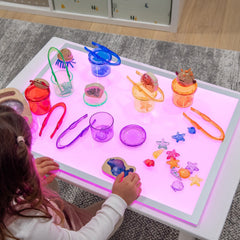 Child playing with colorful toys on a light-up table