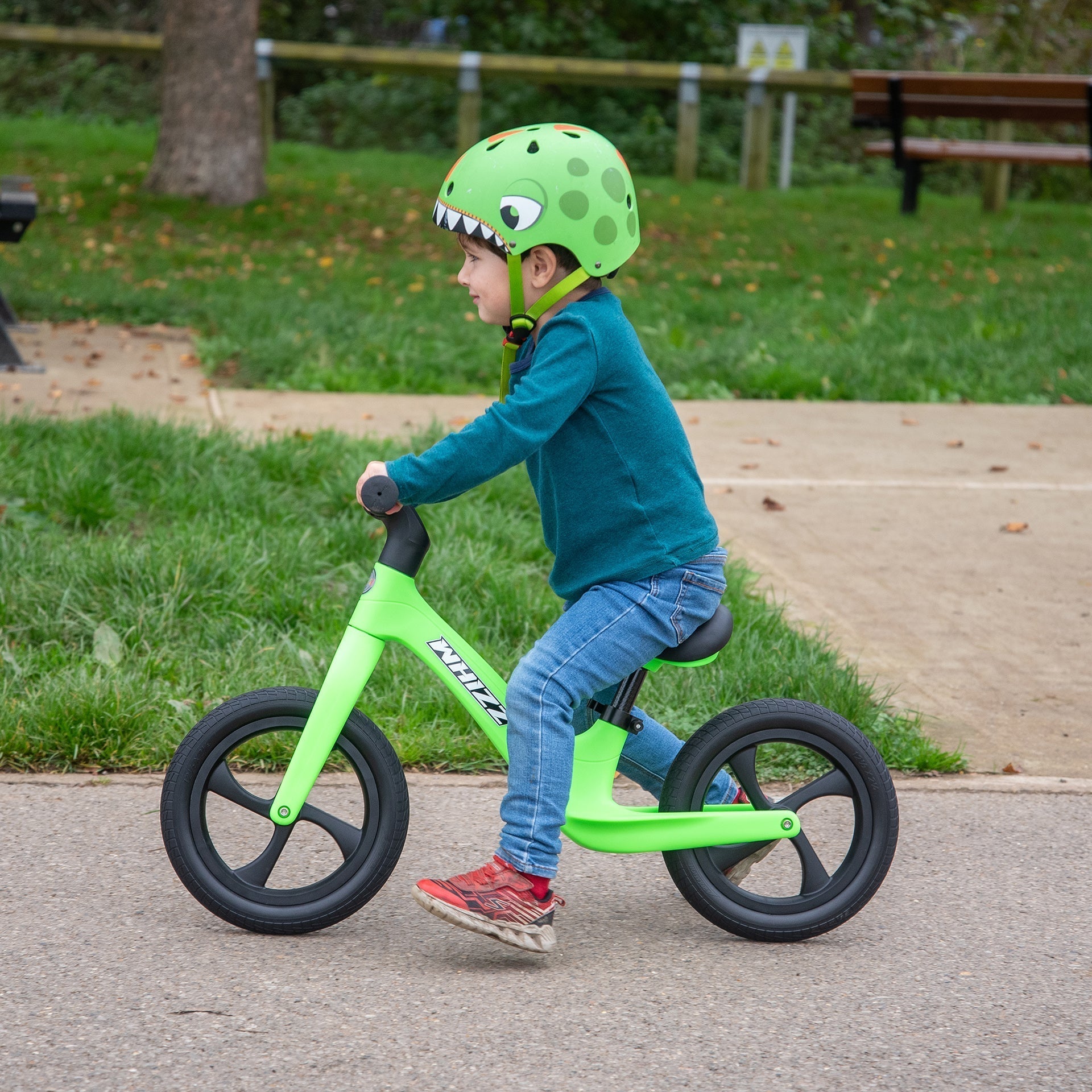 Child riding a green balance bike in a park