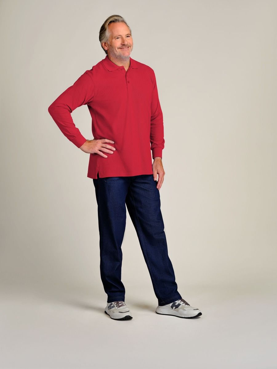 A man modeling a red long-sleeve polo shirt and dark navy pants, standing against a plain light beige studio background.