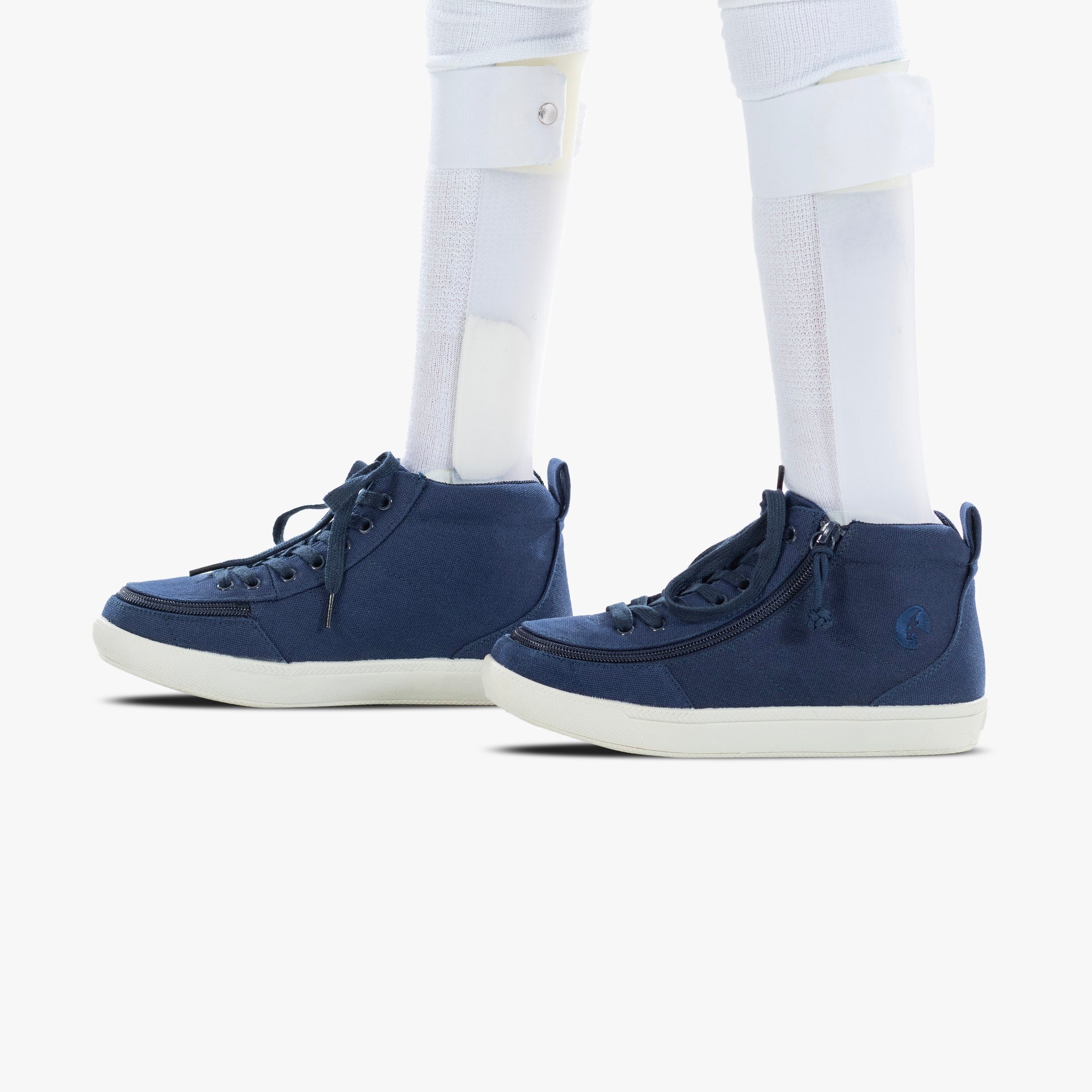 Navy high-top sneakers worn with white pants on a white background