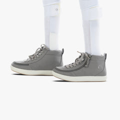 Gray high-top sneakers worn with white pants on a white background