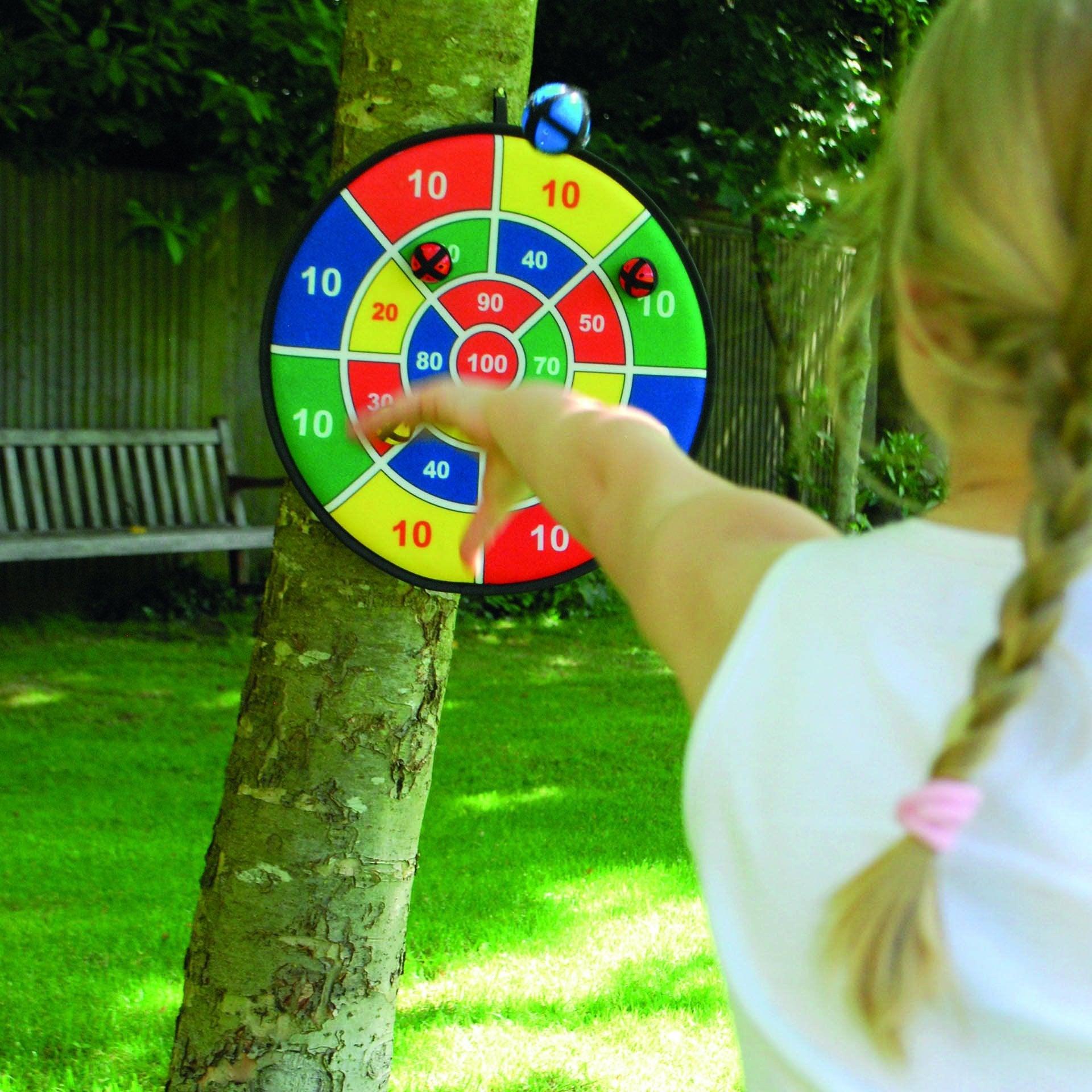 Child playing with a colorful dartboard outdoors
