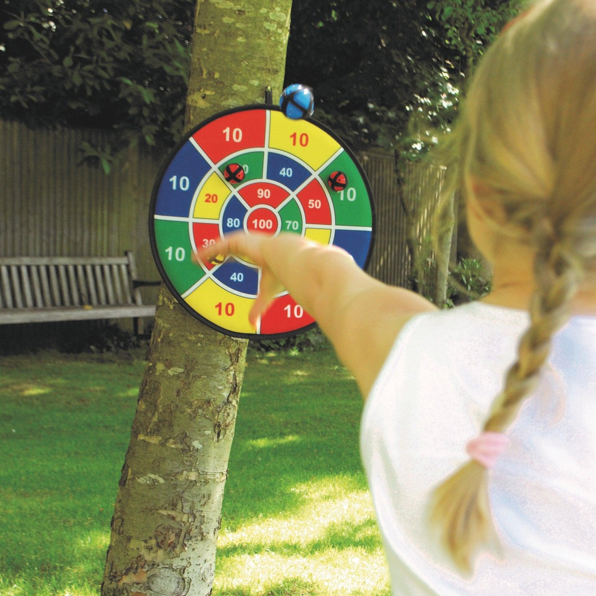 Child playing with a colorful dartboard outdoors