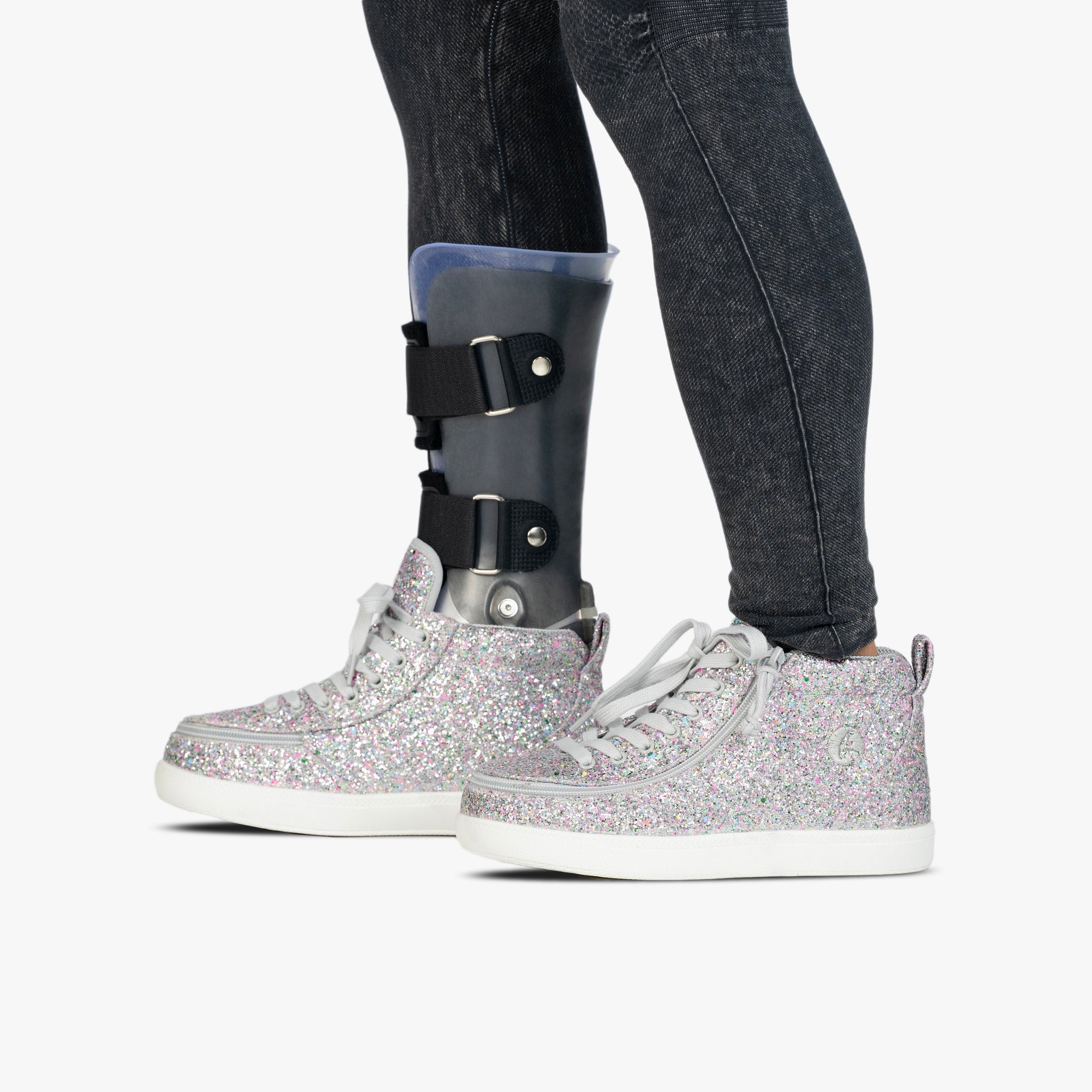 Person wearing a cast on one leg with glittery shoes on a white background