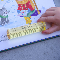 Child's hand holding a paper roll with text on a children's book