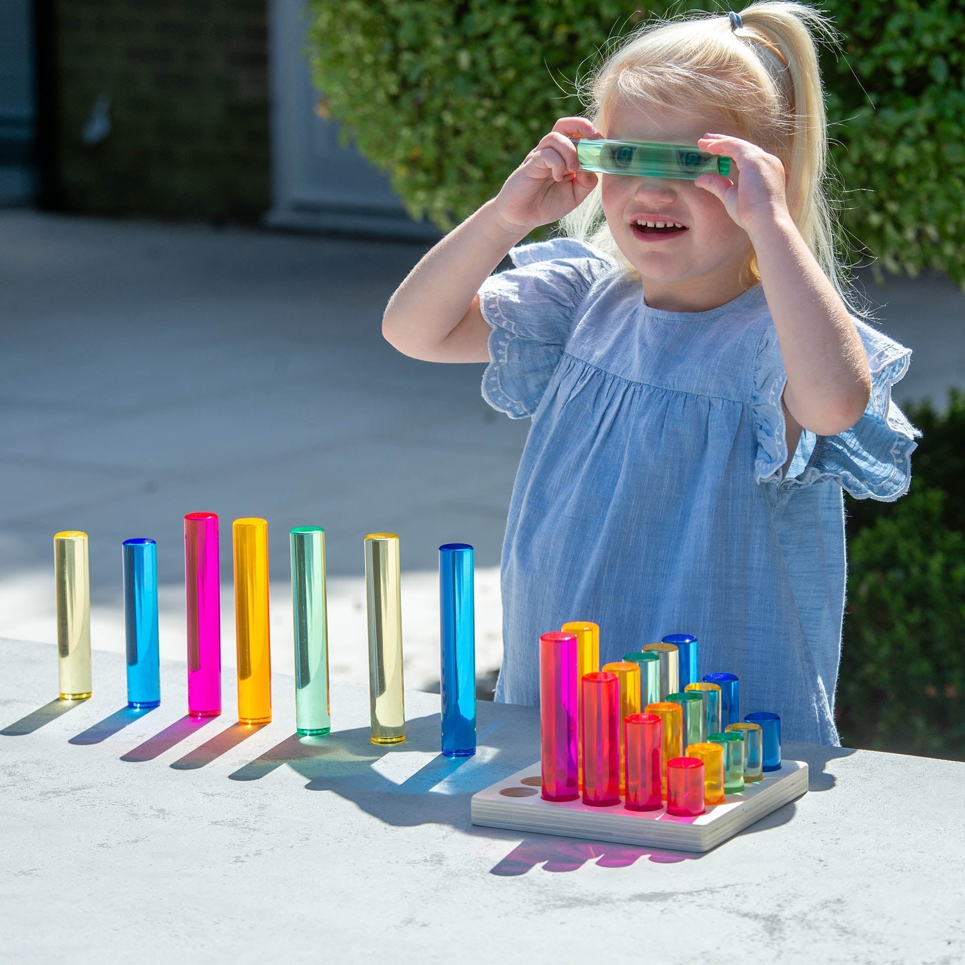 Child playing with colorful transparent tubes on a table outdoors