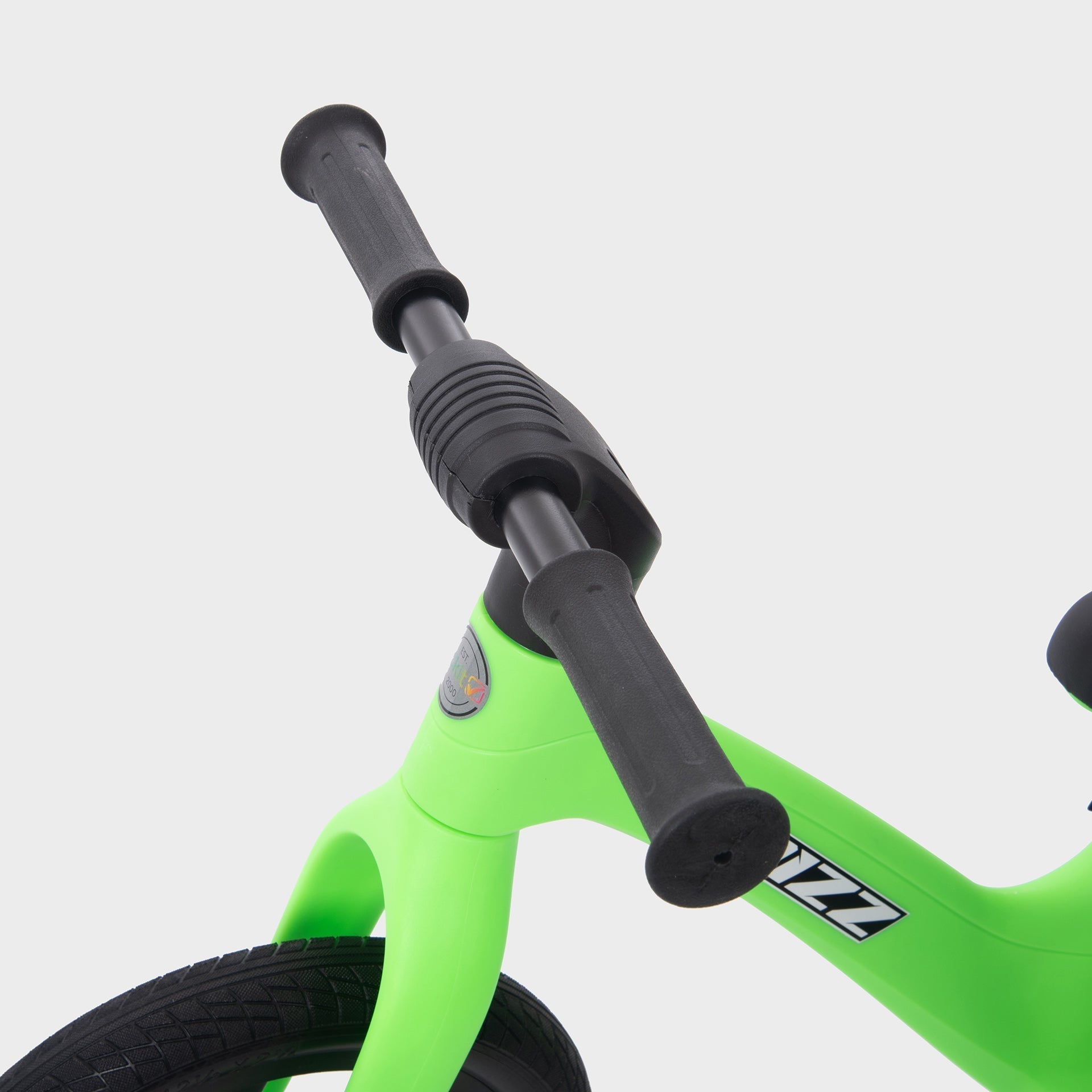 Green balance bike with black handlebar on a light gray background