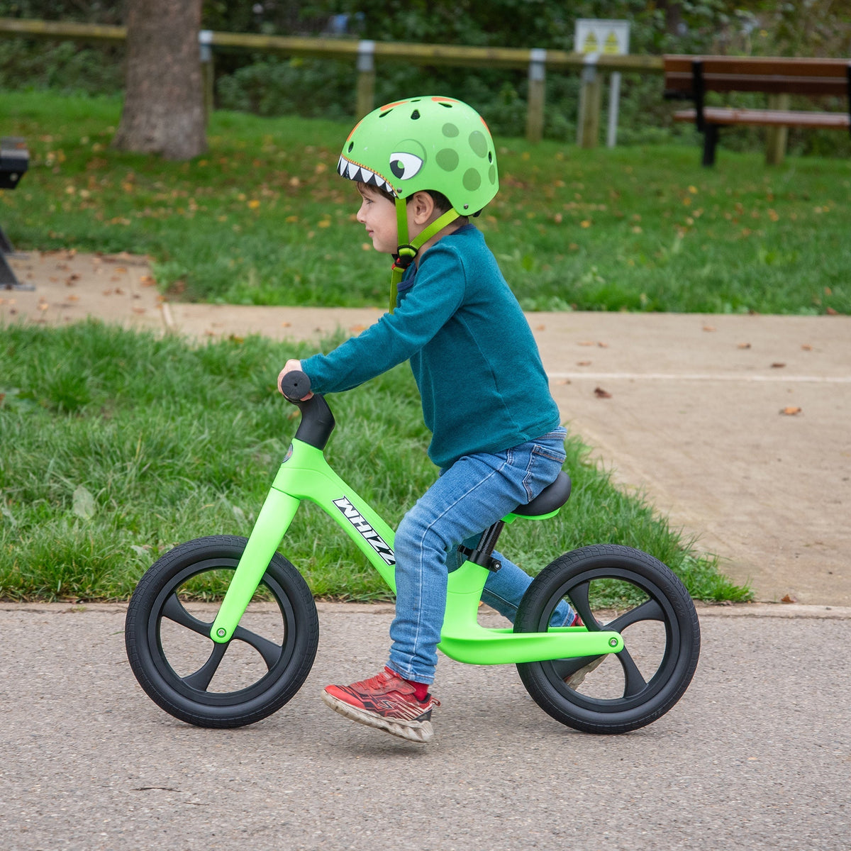 Child riding a green balance bike in a park