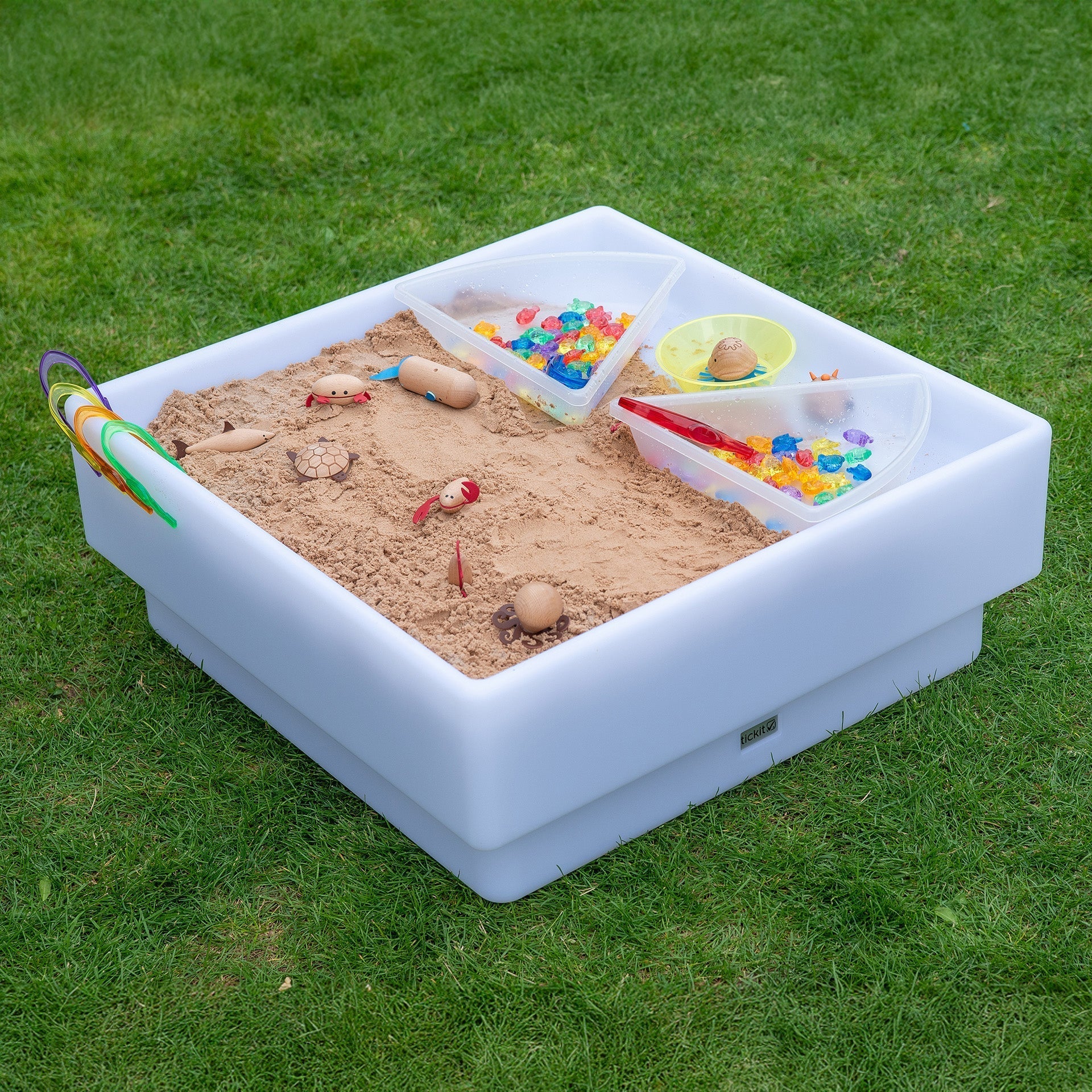 Inflatable sandbox with sand and toys on a grassy background