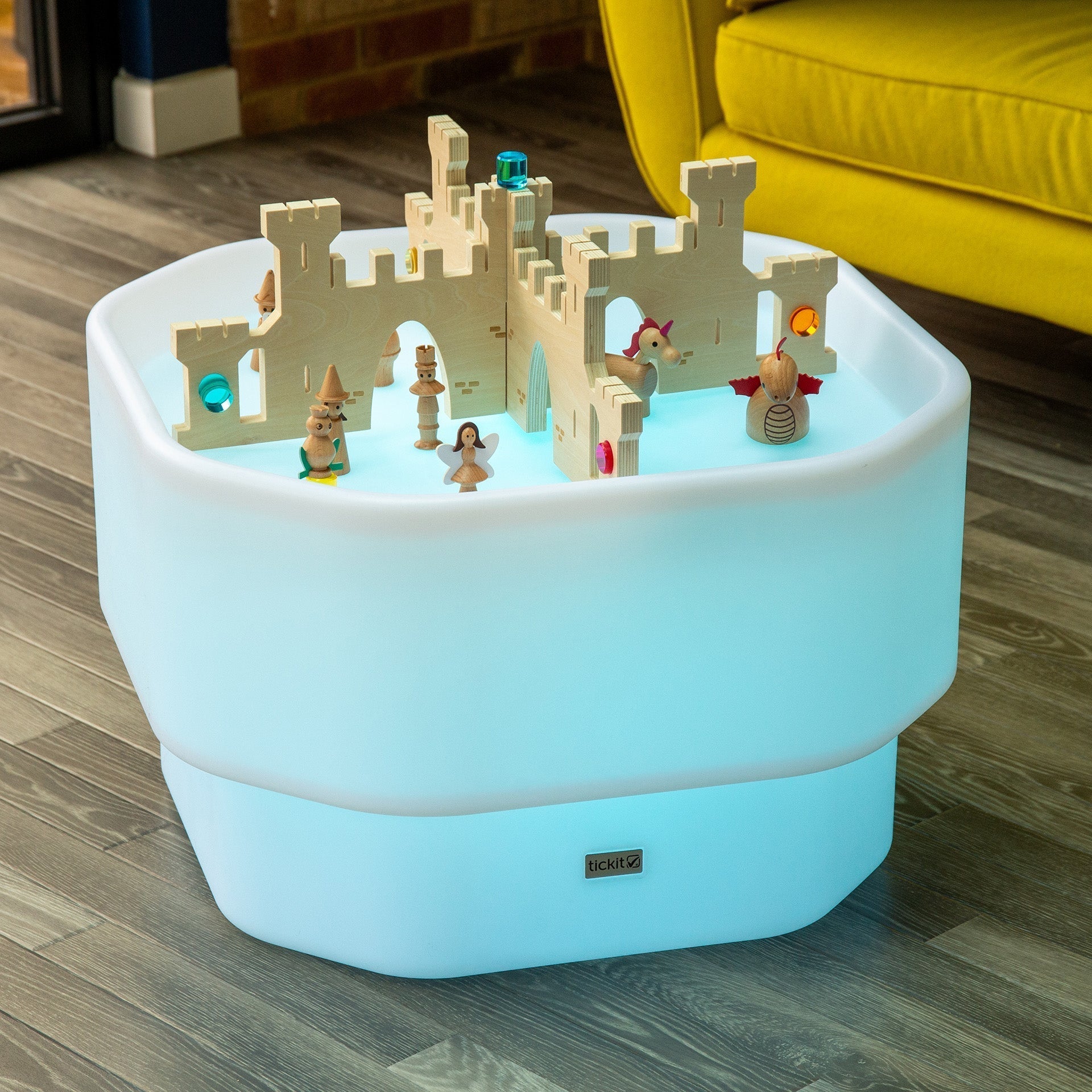 Light-up toy table with a castle structure and figurines on a wooden floor.
