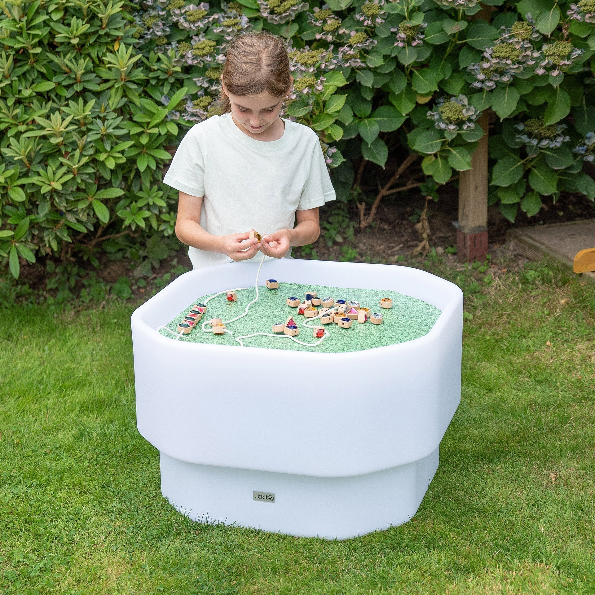 Child playing with toys on a unique outdoor table in a garden setting