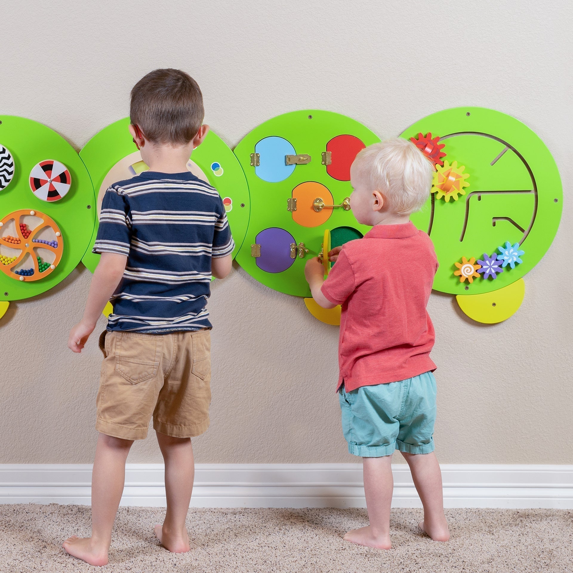 Two children playing with colorful educational wall toys.