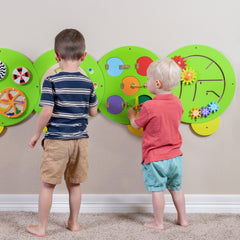 Two children playing with colorful educational wall toys.