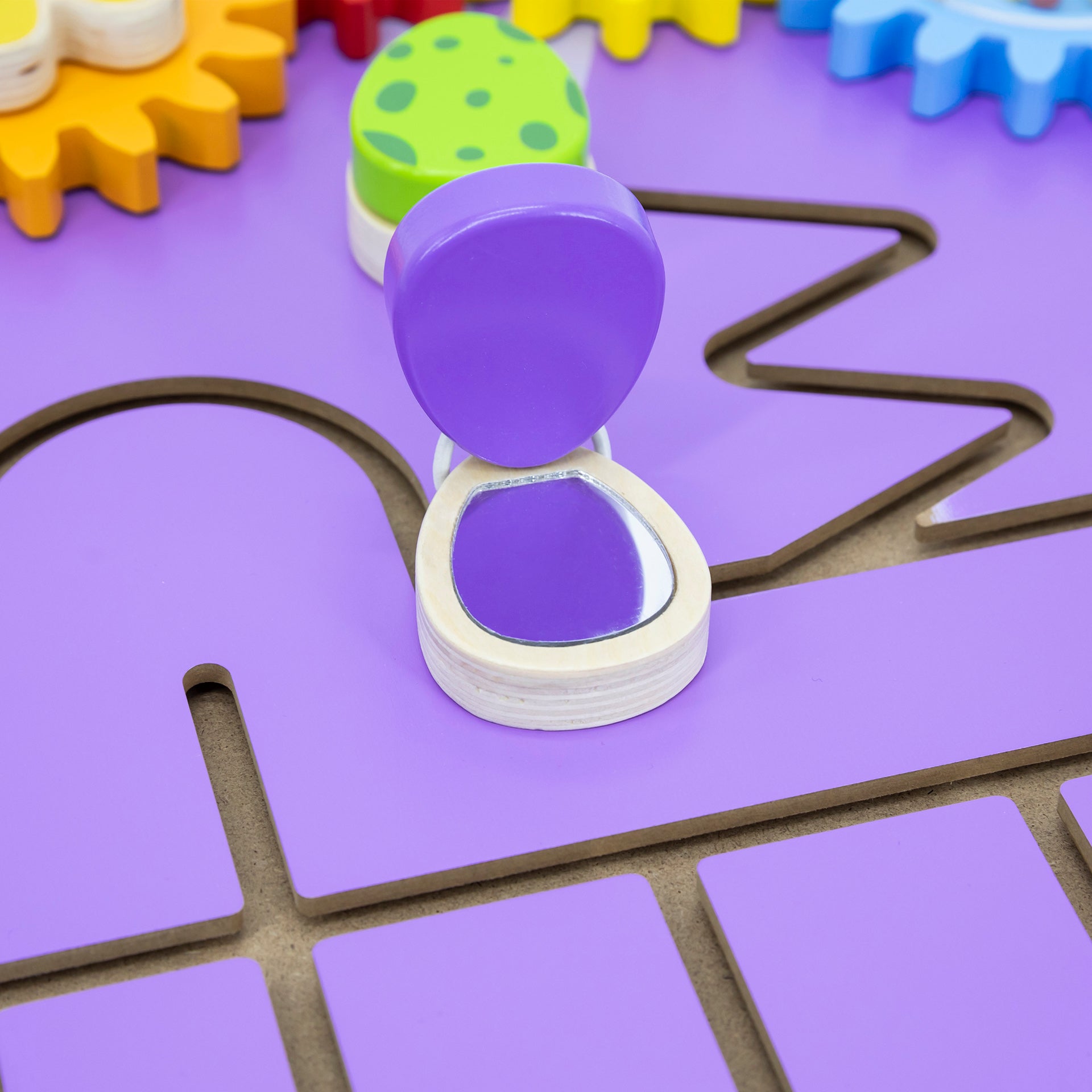 Colorful foam letters on a purple mat with a purple hourglass-like object.