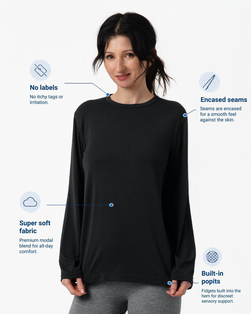 A woman modeling a black long-sleeve top with text callouts highlighting product features: no labels, enclosed seams, super soft fabric, and built-in popits.