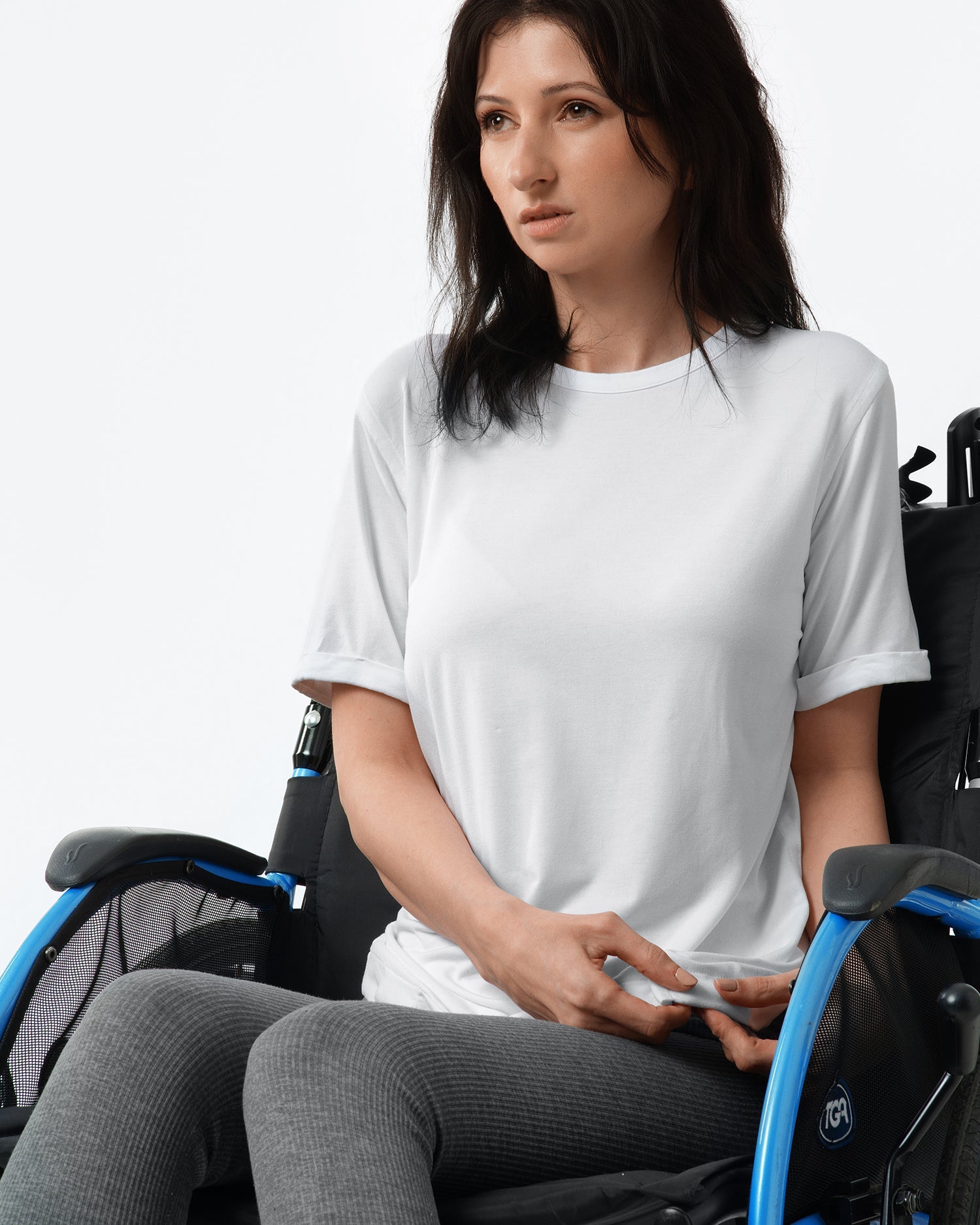 Woman in a wheelchair wearing a white t-shirt on a plain background