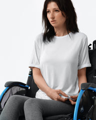 Woman in a wheelchair wearing a white t-shirt on a plain background