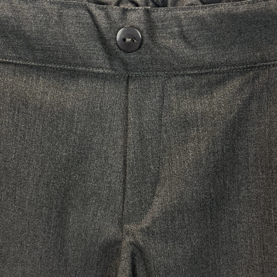 Close-up of dark gray pants with a button detail