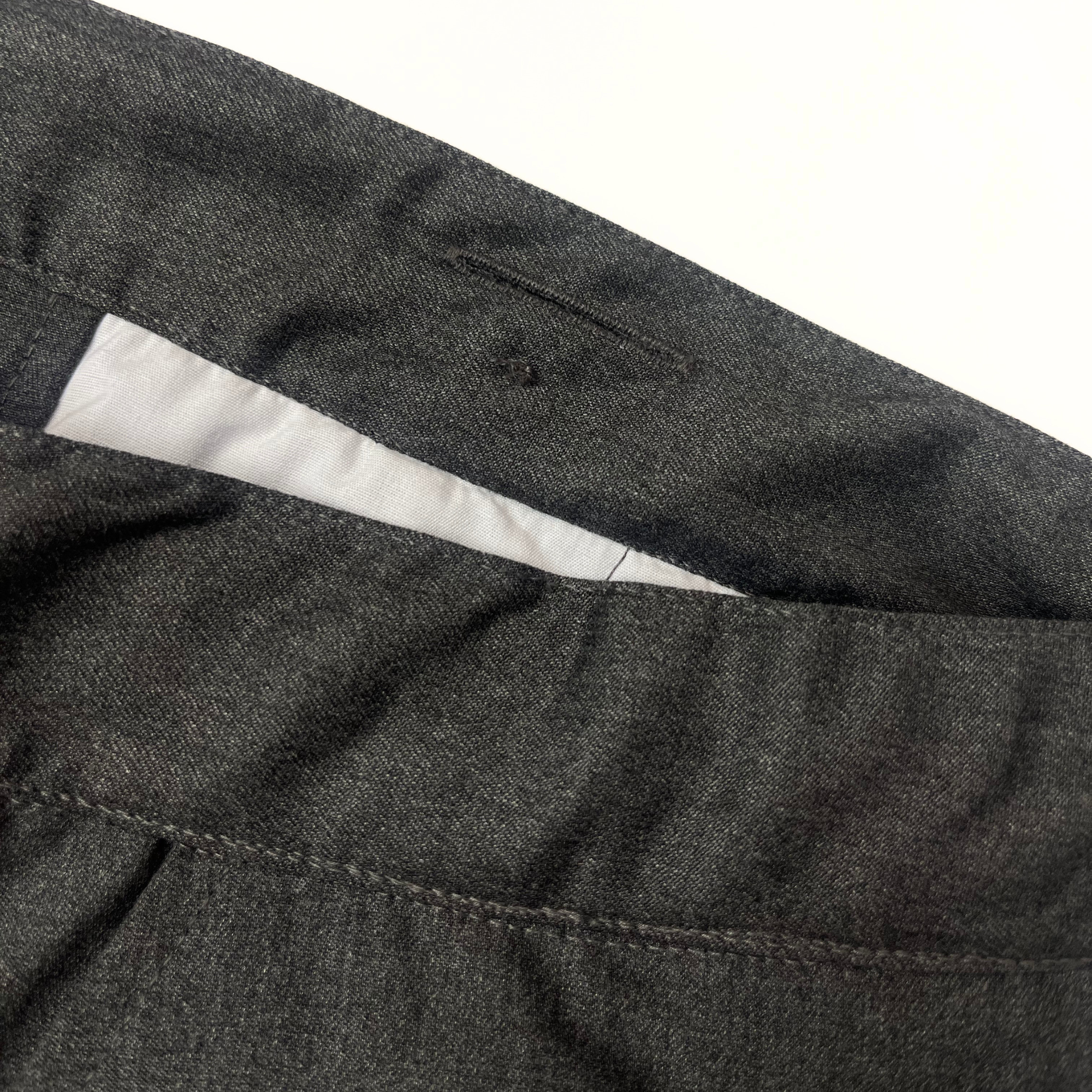 Close-up of dark gray pants with a white lining on a light gray background