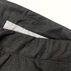 Close-up of dark gray pants with a white lining on a light gray background