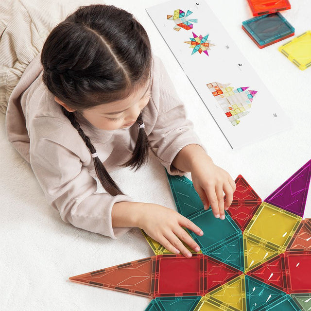 Child playing with colorful magnetic building blocks on a light surface.
