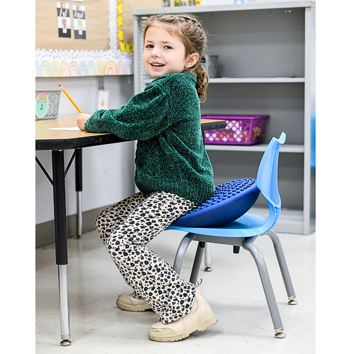 Child sitting at a desk in a classroom with a blue chair