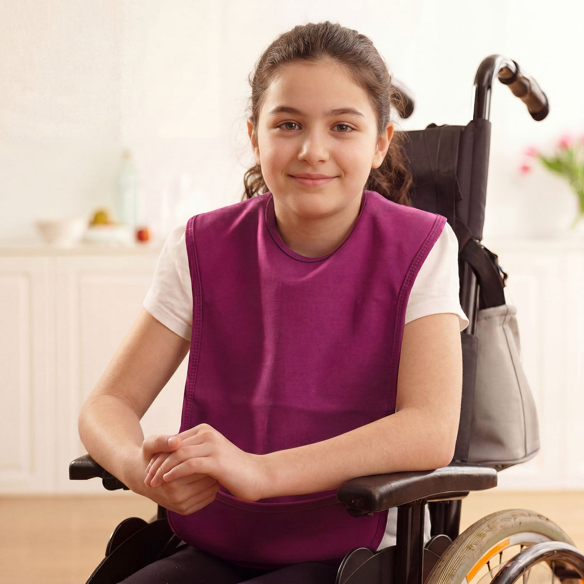 Young girl in a wheelchair wearing a purple vest, smiling indoors.